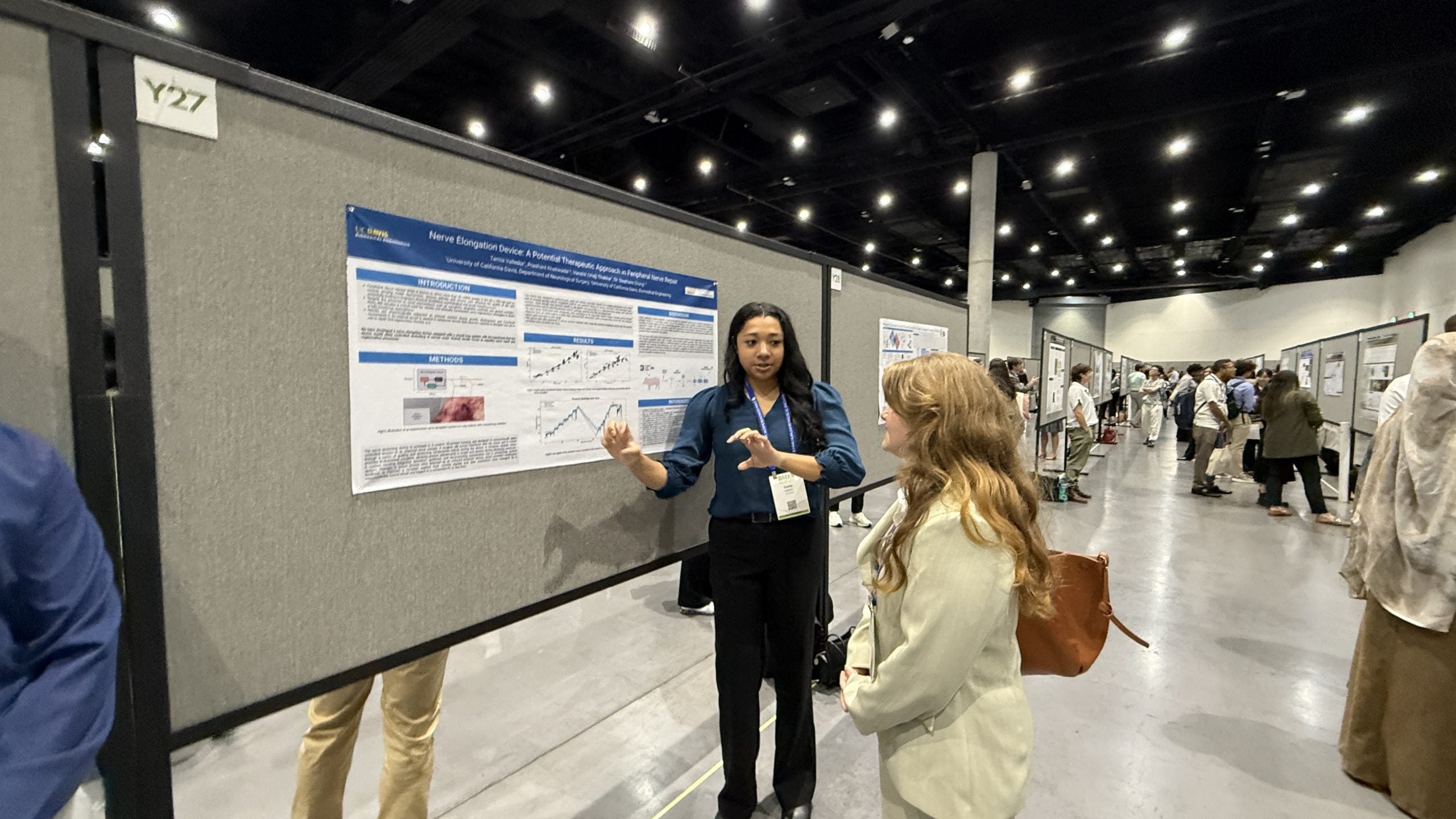 Tamia presents Nerve Elongation Device poster to conference attendee